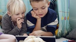 To børn kigger sammen på en tablet.