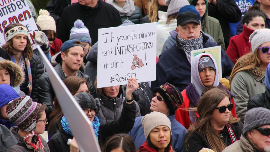 Foto af mennesker til demonstration og skilt med teksten "If your feminism isn't intersectional it ain't shit"
