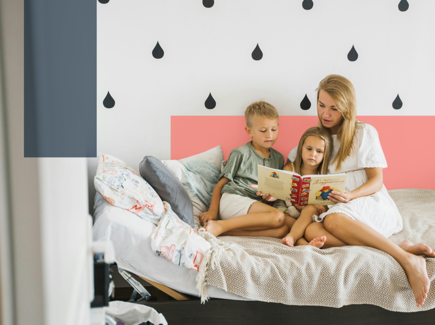 Mor i seng læser med to børn